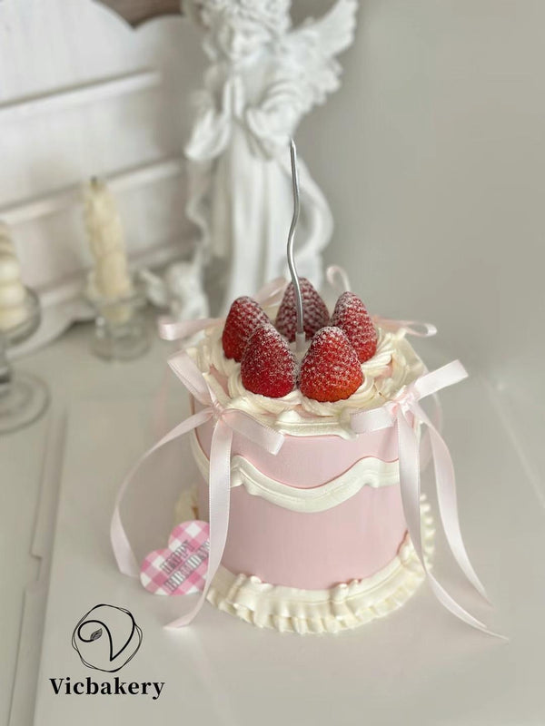 Pink cake decorated with white silk bow and strawberries and pipe